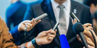 MASS SHOOTING — Developing DETAILS INSIDE Journalists holding microphones interview a person in a suit.