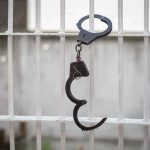 GOVERNOR’S Shock Move FREES PROMINENT Political Figure Handcuffs hanging on white metal bars.