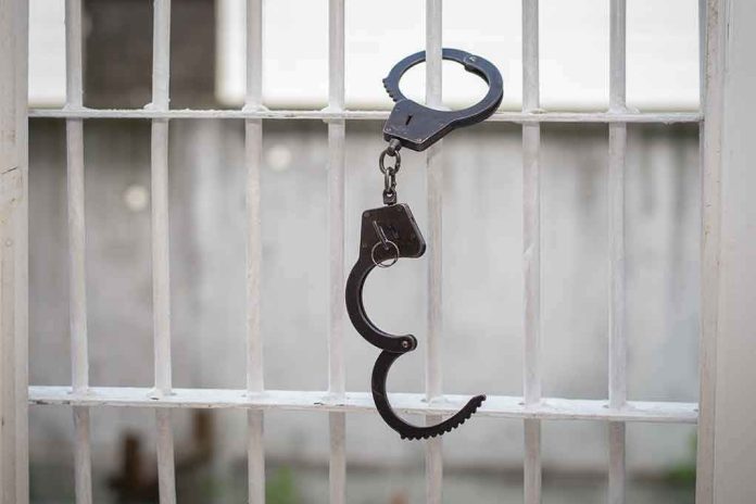 680970664 Handcuffs hanging on white metal bars.