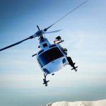 BIZARRE: Car Crash SPIRALS Into a HELICOPTER Snatch! A helicopter flying over a mountainous landscape against a blue sky