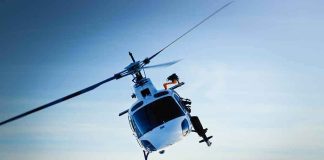 BIZARRE: Car Crash SPIRALS Into a HELICOPTER Snatch! A helicopter flying over a mountainous landscape against a blue sky