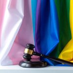 Judge NUKES BIDEN’S Title IX! A gavel resting on a surface in front of colorful pride flags