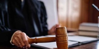 DOJ Clampdown Locks KIDS’ CARE For 20 Years A judge's hand holding a gavel in a courtroom setting