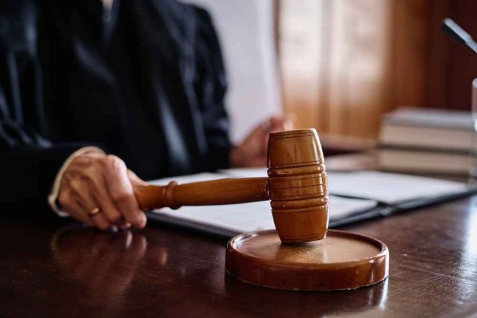 shutterstock_2378803063 A judge's hand holding a gavel in a courtroom setting