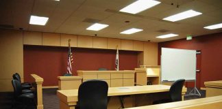 Four-Year VERDICT Upends HEIR’S Dynasty Interior view of an empty courtroom with wooden furniture and American flags