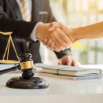 Judge Slams ‘FRAUD’ Deal Protecting Trump Hands shaking over legal documents with gavel and scales.