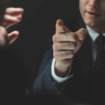 Man in suit pointing a finger during a tense conversation