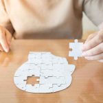 Chilling CHOICE Or BROKEN Brain? Person holding puzzle piece over head-shaped jigsaw on table