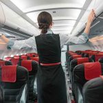 Flight attendant checks overhead bins in empty airplane cabin
