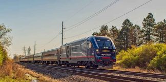 Passenger train on rural tracks passing trees