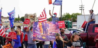 Early Voting BOMBSHELL — Trump Drops In! Crowd of people at a political rally holding flags and signs