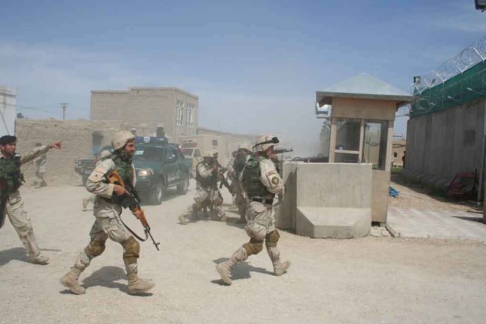 shutterstock_1931171405 Soldiers in desert uniforms run past a checkpoint amid dust
