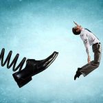 Businessman propelled backward by a giant spring-loaded shoe