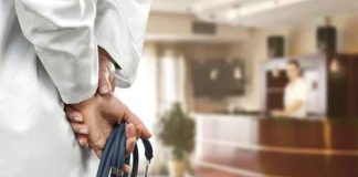 A doctor holding a stethoscope behind their back in a hospital reception area