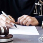 MASSIVE Cancer Claims QUIETLY Cashed Out Judge writing at desk with gavel and Lady Justice statue