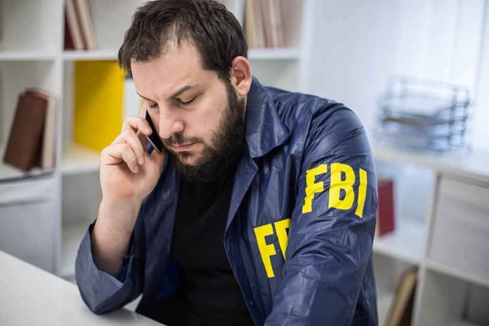 shutterstock_622709600 Man in FBI jacket talking on a phone at a desk