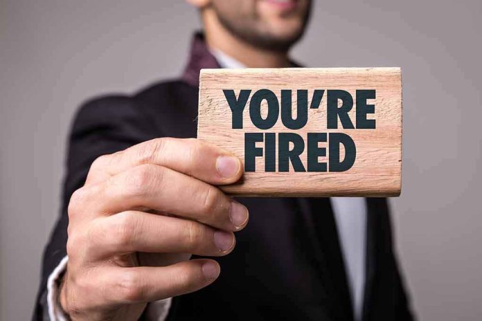 shutterstock_624857621 Man in suit holding a wooden sign that says You're Fired