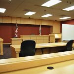 Judge IGNORES First Amendment — Verdict EXPLODES Interior view of an empty courtroom with wooden furniture and American flags