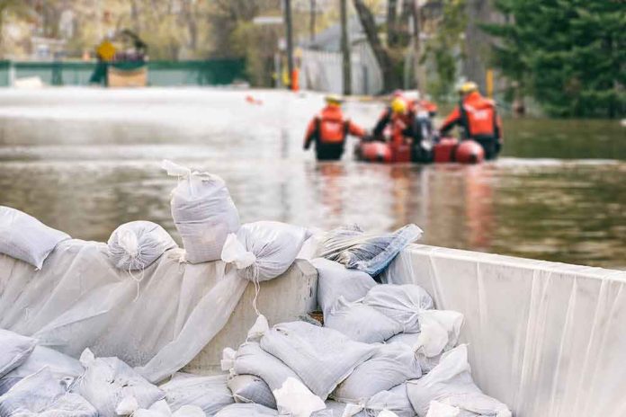 shutterstock_705371167 Sandbags stacked near a flooded street with rescue workers in a boat