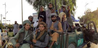 Taliban Ban EXPOSED — Boys Still HUNTED! Armed men sitting on a pickup truck.