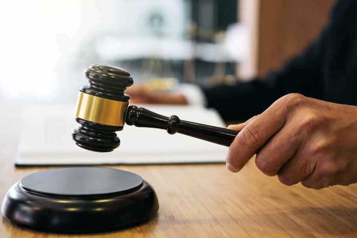 shutterstock_1023698749 Judge's hand holding a gavel over a sound block
