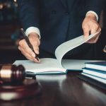 Doctor-Assisted Death SIGNED — Judge Says HOLD UP! Lawyer signing documents at a desk with gavel and scales