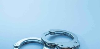 Metal handcuffs on a light blue surface