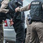 Sharia Panic ERUPTS — 22 Hauled OFF Police officers arresting a person beside a car