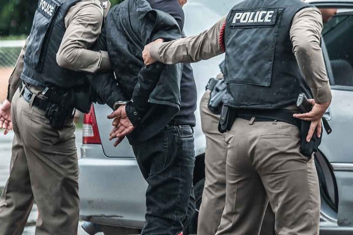 shutterstock_1137889661 Police officers arresting a person beside a car