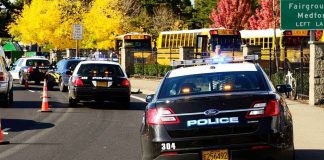 Police cars with lights on near school buses on a city street