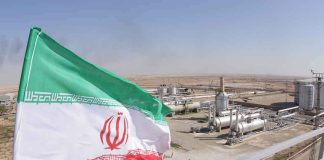 Iran flag over an oil and gas facility in a desert landscape