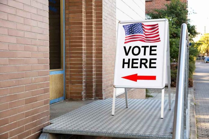 shutterstock_1239383353 Sidewalk sign with American flag directing to a polling place