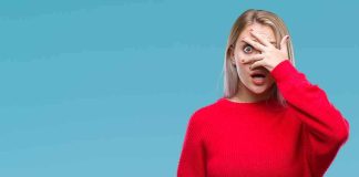 Three-Way SHOCK Jolts State SENATE Woman in red sweater peeking through fingers with a surprised expression