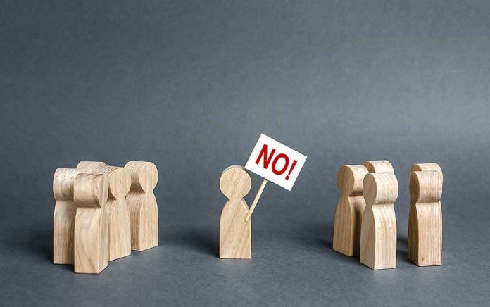 shutterstock_1488375128 Wooden figure holding a sign saying NO between two groups