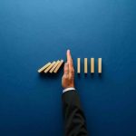 TOP MAYOR Blocks ICE — Public Safety GONE! Hand stopping falling wooden dominoes on blue background