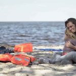 Beach Day Turns BATTLEFIELD — Kids Among Dead Mother hugging child on a beach near life jackets
