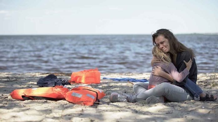 shutterstock_1539381965 Mother hugging child on a beach near life jackets