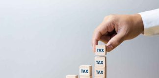 Pension TIME BOMB Triggers Costly TAX Hike Hand stacking wooden blocks labeled TAX into ascending columns