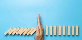 Judge Blocked It — ICE Did It Anyway! Hand stopping falling wooden dominoes on blue background
