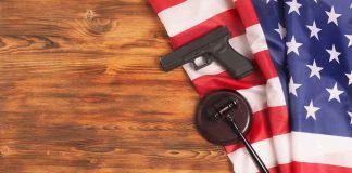 Handgun and judge's gavel on American flag over wooden table