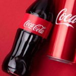 Coke’s Filter BACKFIRES — Boycott ERUPTS Coca-Cola bottle and cans on red background