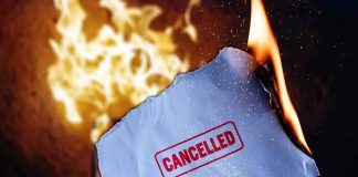 VISA Purge Looms — 200,000 On The Line Burning paper stamped cancelled held by hand