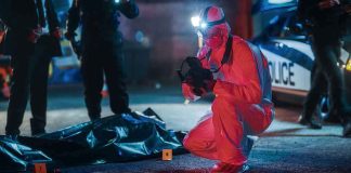 forensic investigator photographs crime scene evidence at night