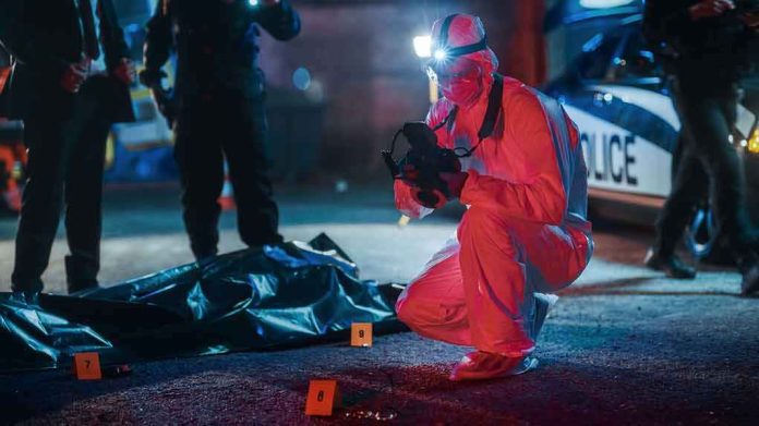 forensic investigator photographs crime scene evidence at night