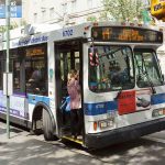 Free Bus Talk CREATES Billion-Dollar Hole A woman boarding a clean air hybrid electric bus at a city stop