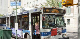 Free Bus Talk CREATES Billion-Dollar Hole A woman boarding a clean air hybrid electric bus at a city stop