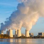 Cooling towers emitting steam at a power plant by a river
