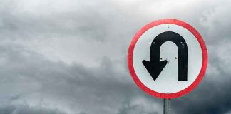 U-turn road sign against dark stormy sky