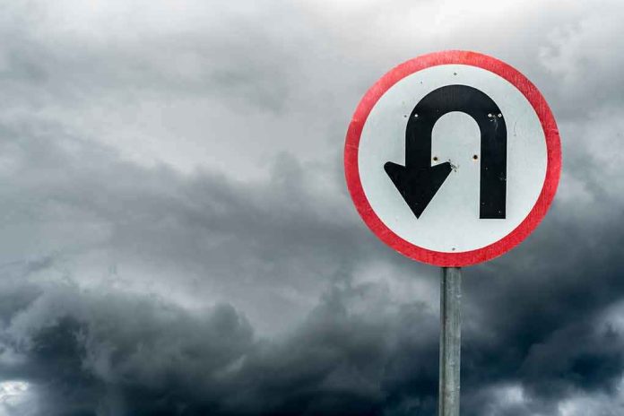 U-turn road sign against dark stormy sky