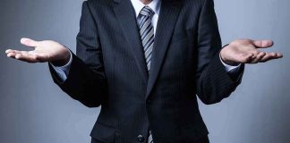 Businessperson in suit shrugging with open hands